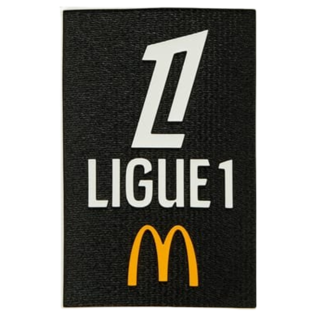 Black patch with white 'Ligue 1' logo and yellow 'M' on a white background